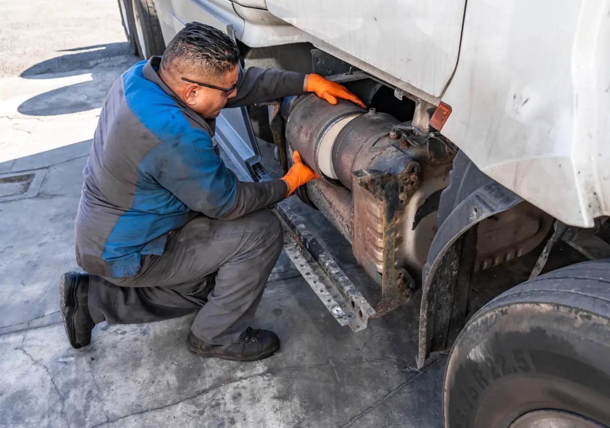 Diesel mechanic inspecting a heavy-duty truck DPF and emissions system during repair